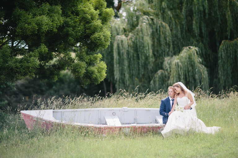 bride and groom sitting in a rustic boat green forest Te Horo Beach wedding natural light