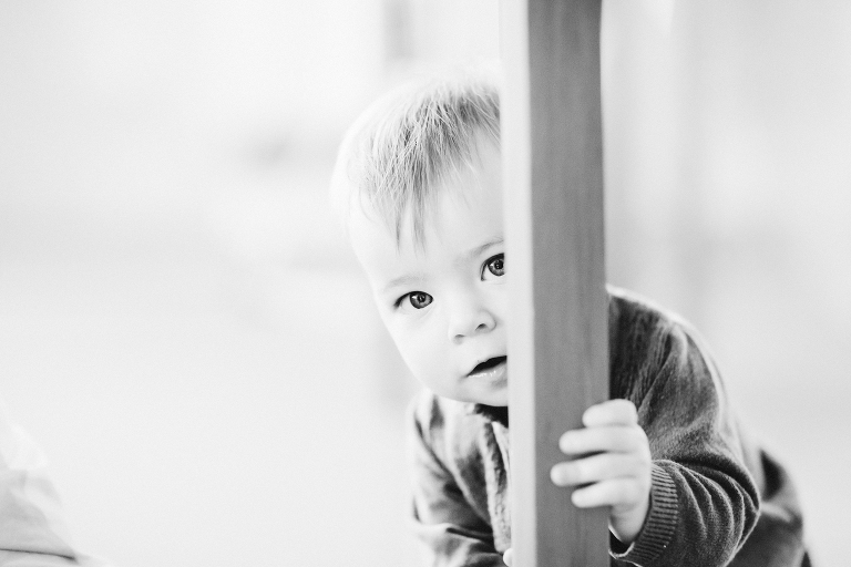 baby peeking around pole Wellington in home family photography black and white
