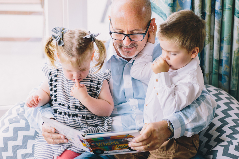 grandfather with toddler on his lap reading Wellington in home family photography natural light