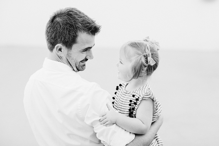 dad holding toddler daughter smiling Wellington in home family photography natural light black and white