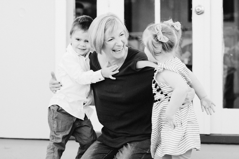 grandmother laughing with toddler girl and boy Wellington in home, family photography, natural light black and white 