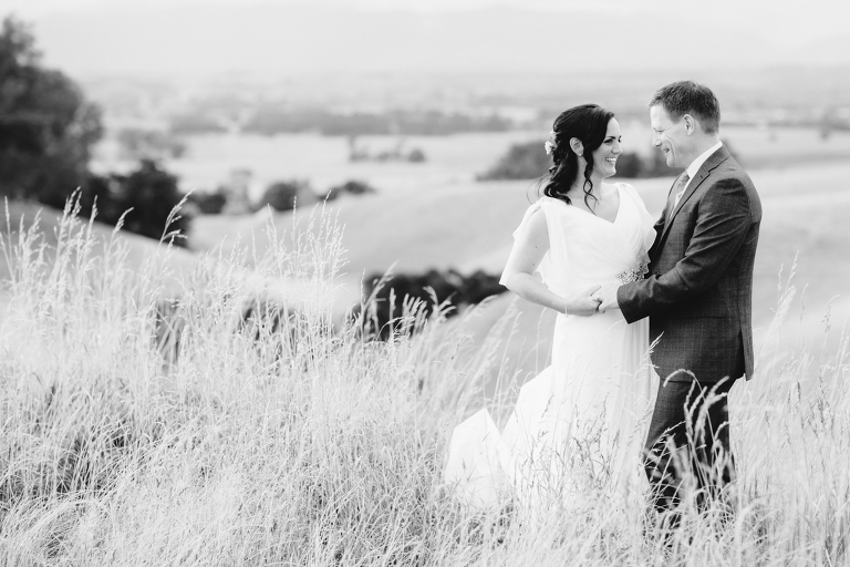 bride and groom holding hands staring at each in a field Burnside Church Martinborough Wedding natural light black and white