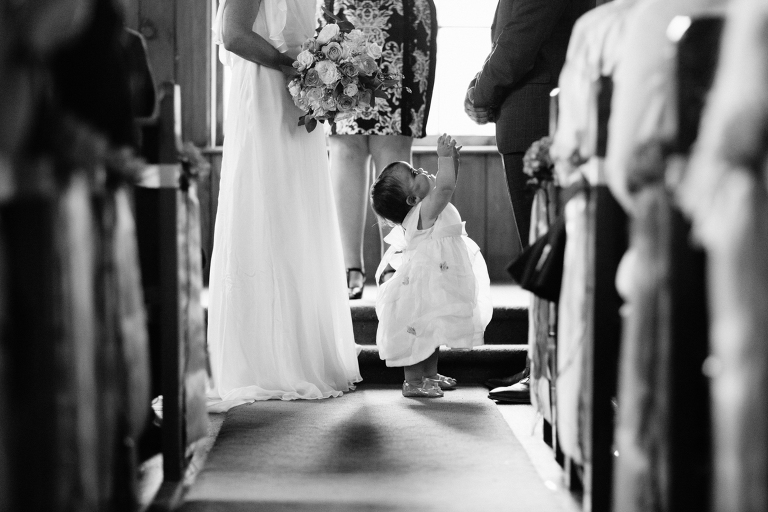 bride holding bouquet with baby beside her at ceremony Burnside Church Martinborough Wedding natural light black and white