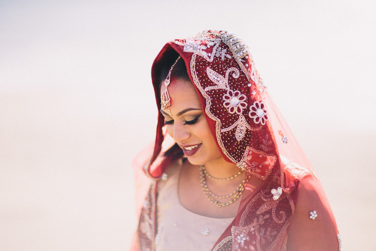 bride looking down in traditional sari by water on beach Pauatahanui Inlet Wellington wedding natural light 