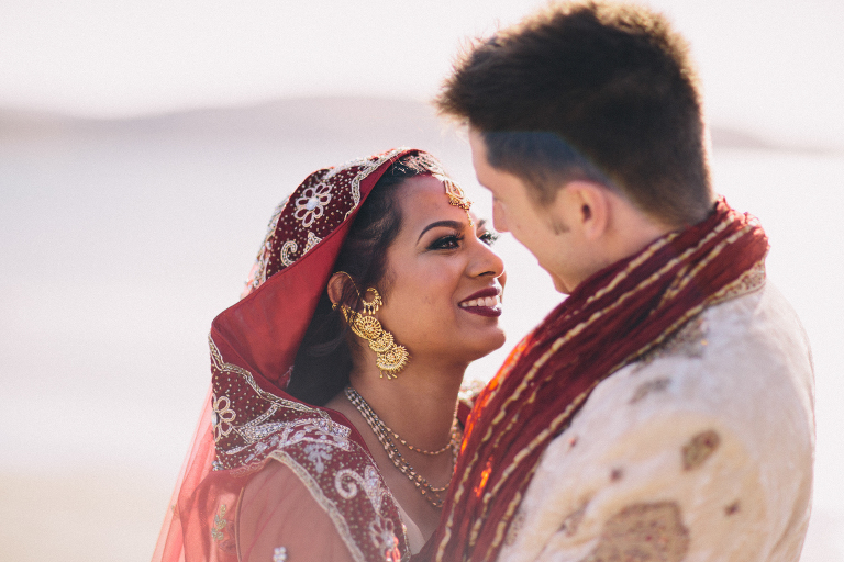 bride and groom looking into each others eyes smiling by water on beach Pauatahanui Inlet Wellington wedding natural light 