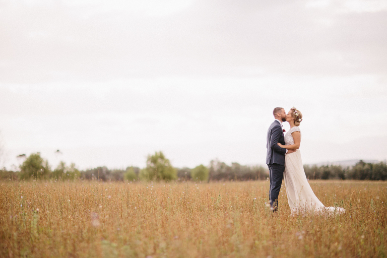 bride and groom kissing in rustic field Martinborough Brackenridge Estate wedding natural light 