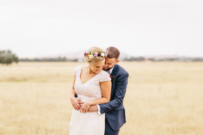 bride and groom holding each other in rustic field Martinborough Brackenridge Estate wedding natural light 