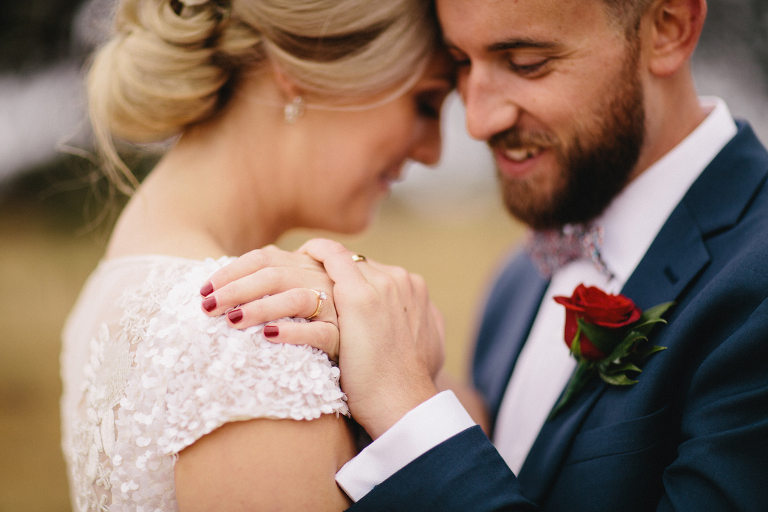 bride and groom smiling at each other close up of hands in rustic field Martinborough Brackenridge Estate wedding natural light 