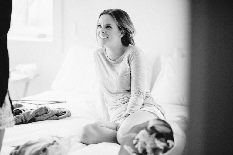 bride smiling at friend on bed Martinborough Brackenridge Estate wedding black and white