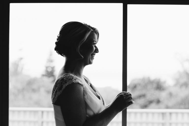  Bridesmaid smiling at bride getting dressed Riversdale Wedding natural light black and white