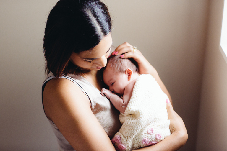 mom holding baby girl and stroking her head Newborn Photography Wellington natural light 