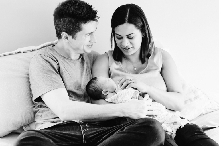 mom and dad holding baby girl on bed Newborn Photography Wellington natural light black and white