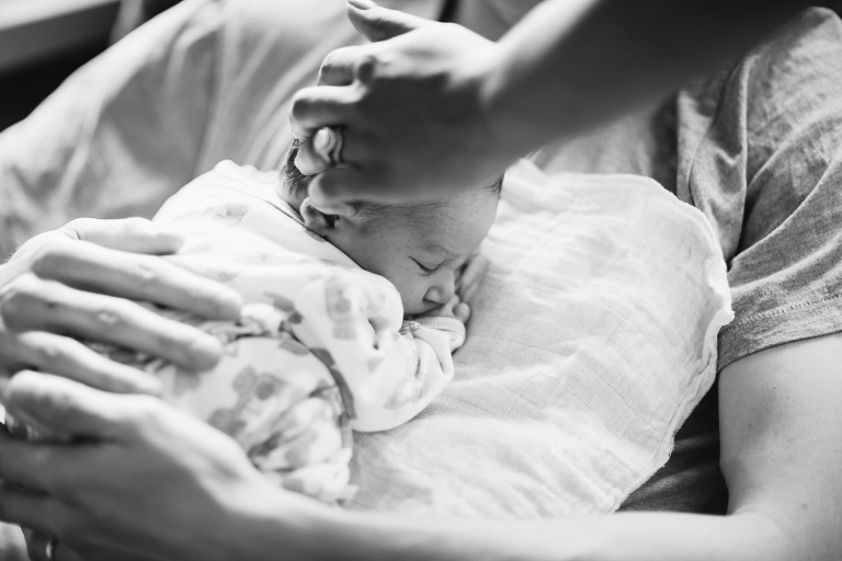 mom stroking baby girls head on dad's chest Newborn Photography Wellington black and white