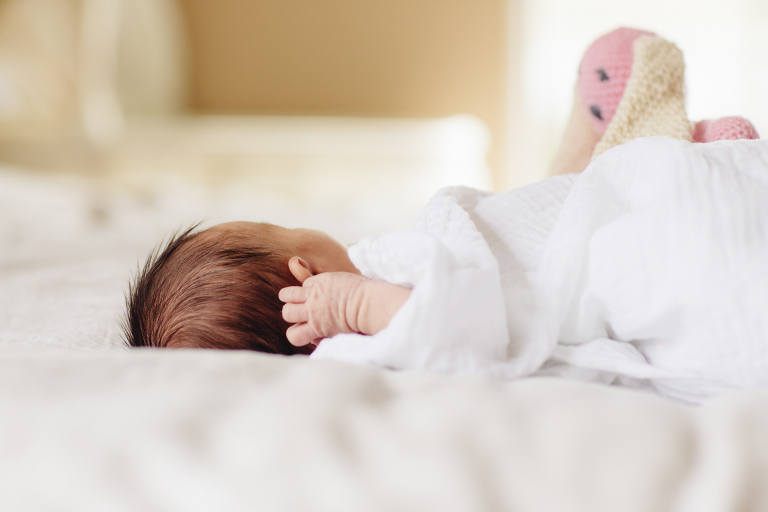 baby girl on bed wrapped in blanket foot in the air Newborn Photography Wellington natural light