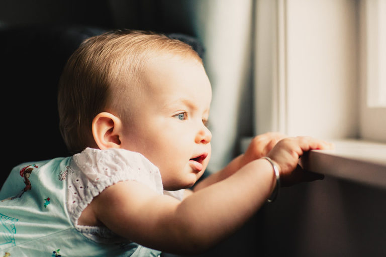 baby girl looking out the window natural light In-Home Photography First Birthday Party