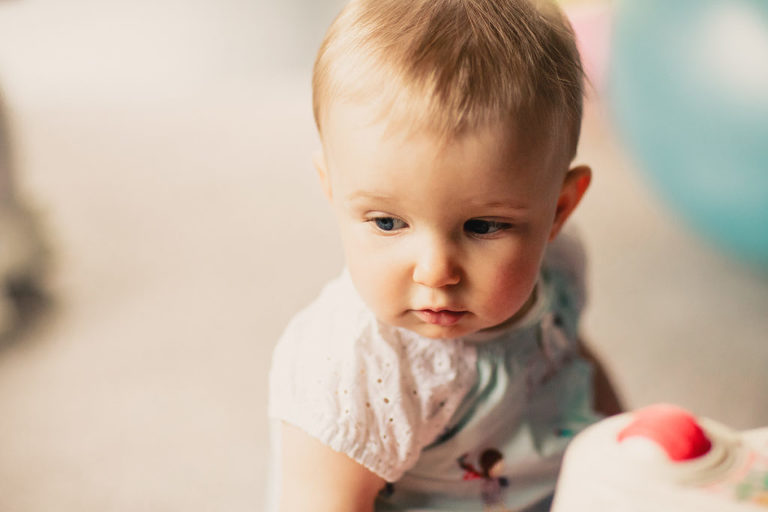 baby girl playing on the floor natural light In-Home Photography First Birthday Party