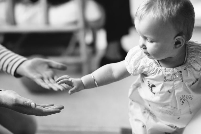 baby girl playing with adults on the floor black and white natural light In-Home Photography First Birthday Party