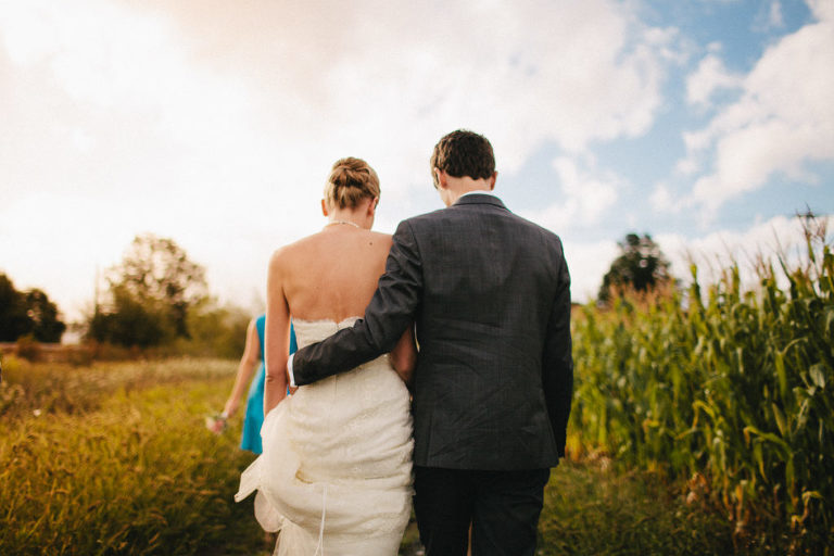 bride and groom standing outside in field from behind natural light Wellington rainy day wedding
