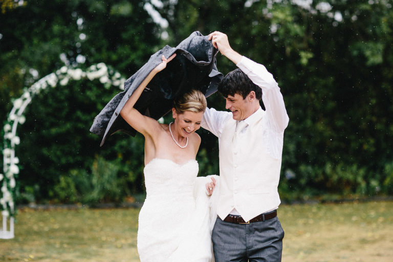 bride and groom using jacket as and an umbrella Wellington natural light rainy day wedding