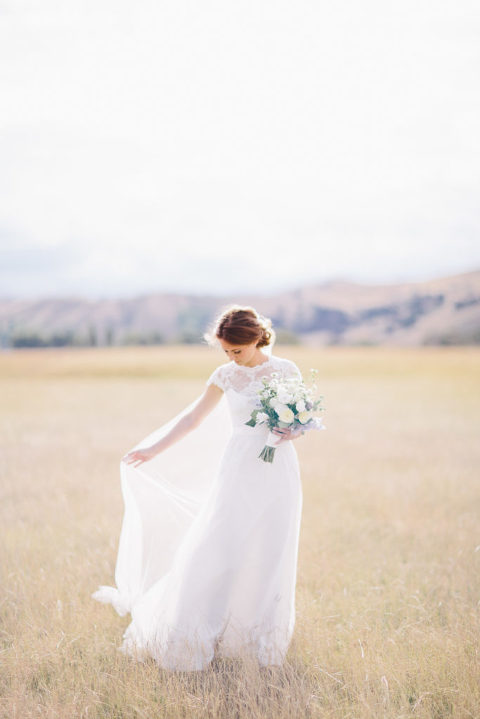 bride holding dress in field with bouquet natural light Wellington wedding