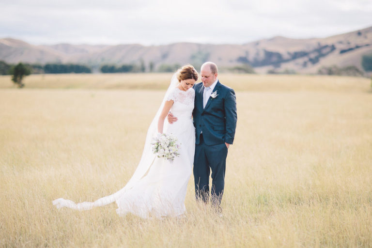 bride and groom in field with bouquet embracing natural light Wellington wedding