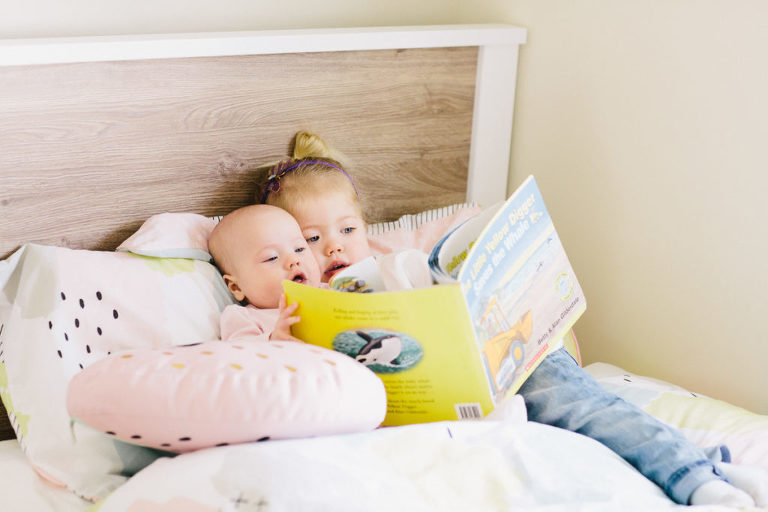 kid sisters ion bed reading book smiling natural light Wellington family photography