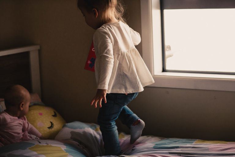 little girl jumping on the bed smiling natural light Wellington family photography